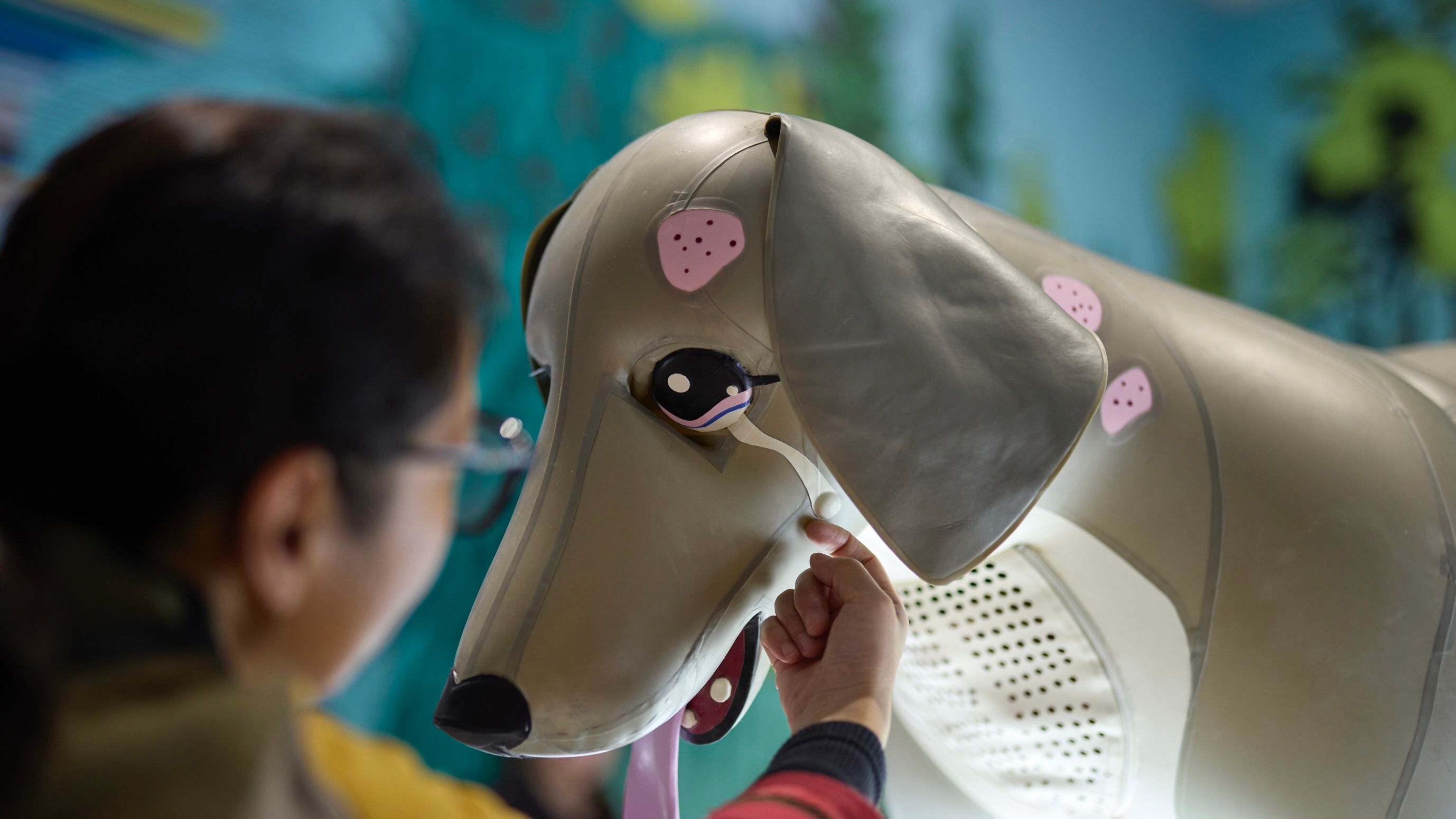 Side profile of an inflatable dog being pet by a human on the side of face. 