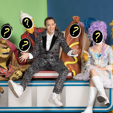 Zoë Coombs Marr dressed as a variety show host, surrounded by costumed characters with question marks superimposed on their faces