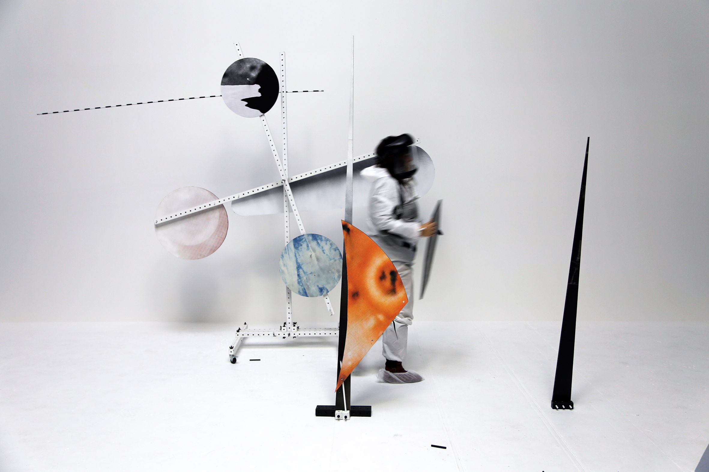 A person, visibly in motion arranges various circle shaped pieces on the structures surrounding them.