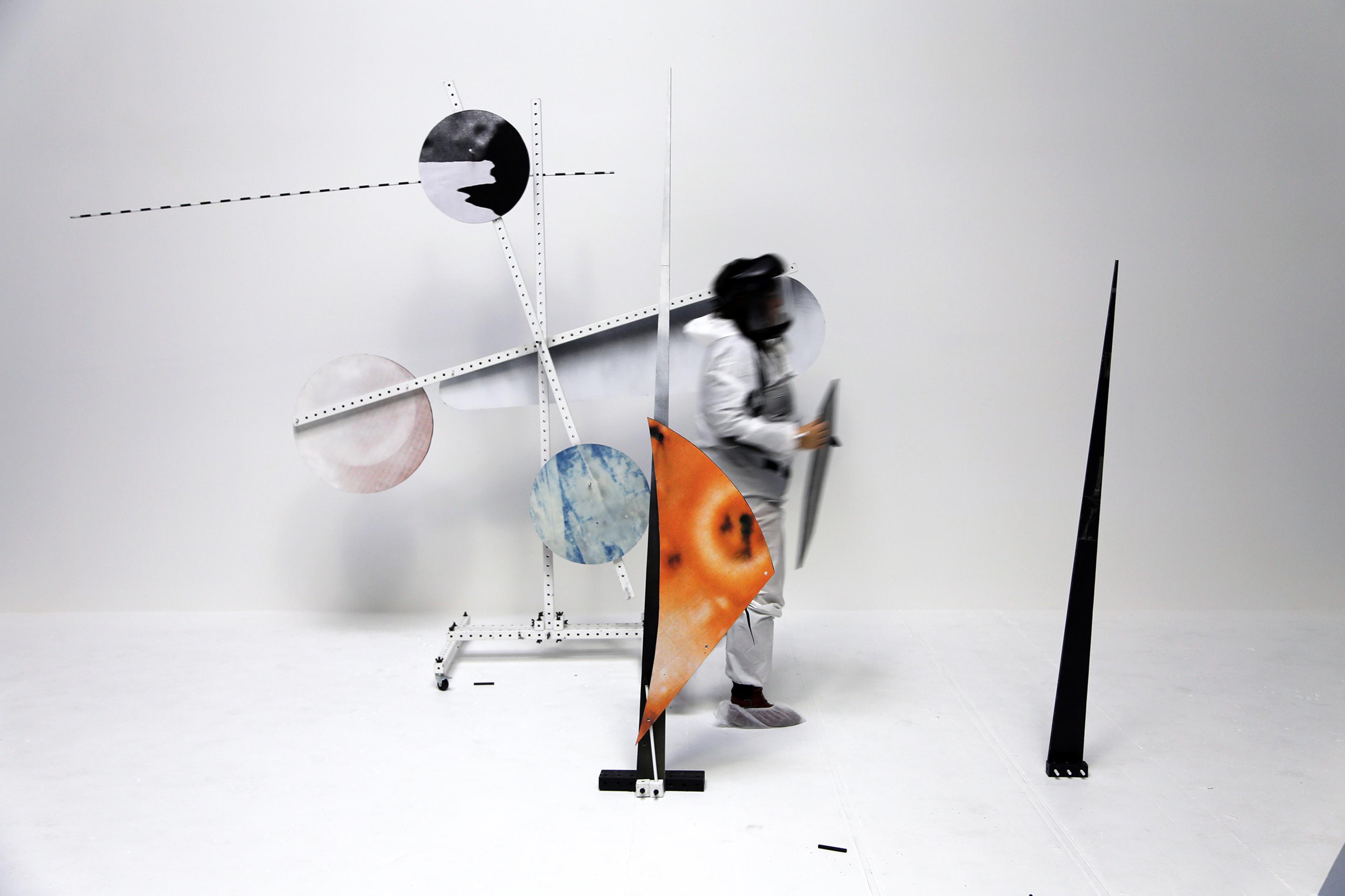 A person, visibly in motion arranges various circle shaped pieces on the structures surrounding them.