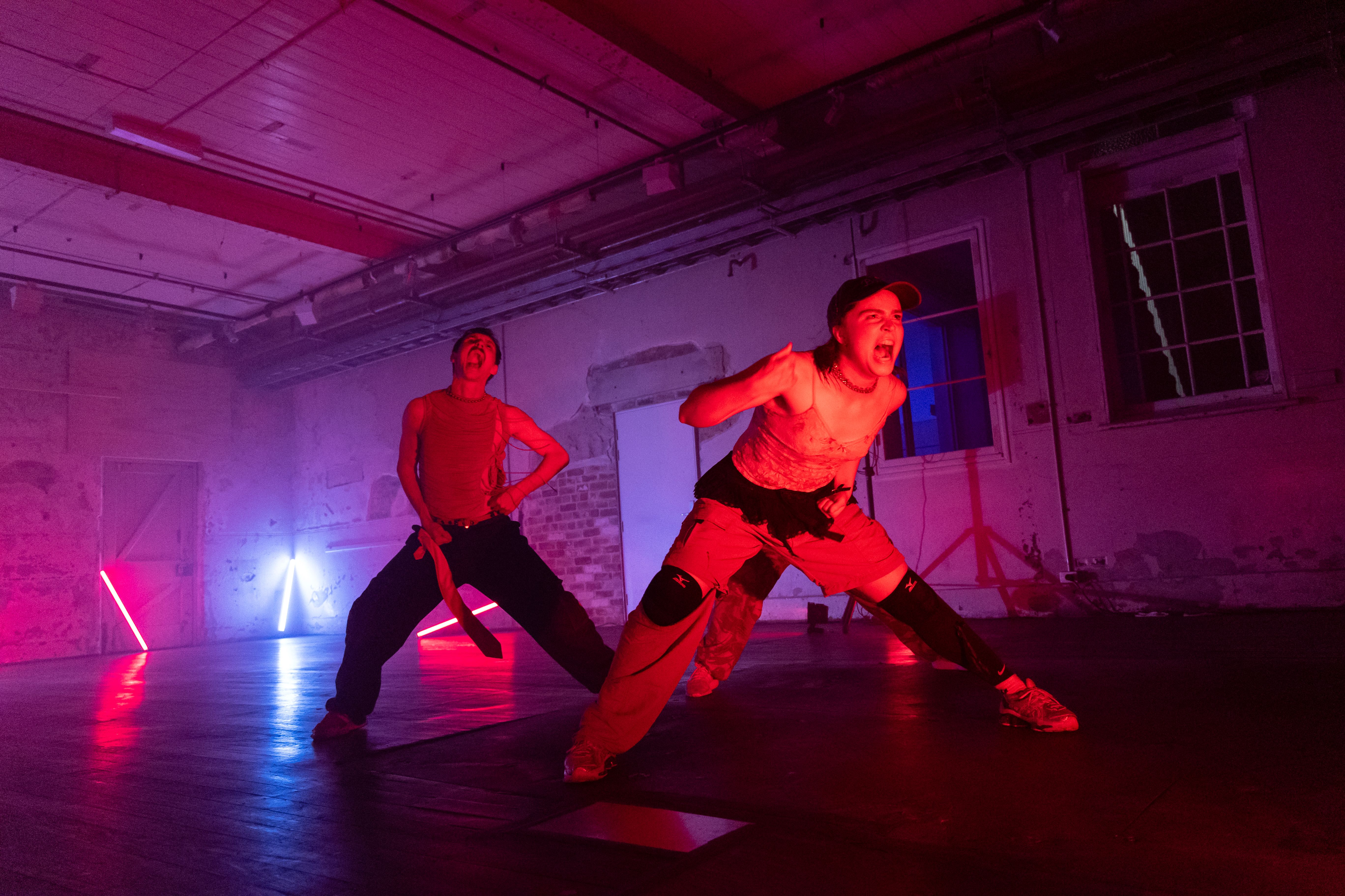 A trio of dancers pose in an open leg stance and appear to be screaming