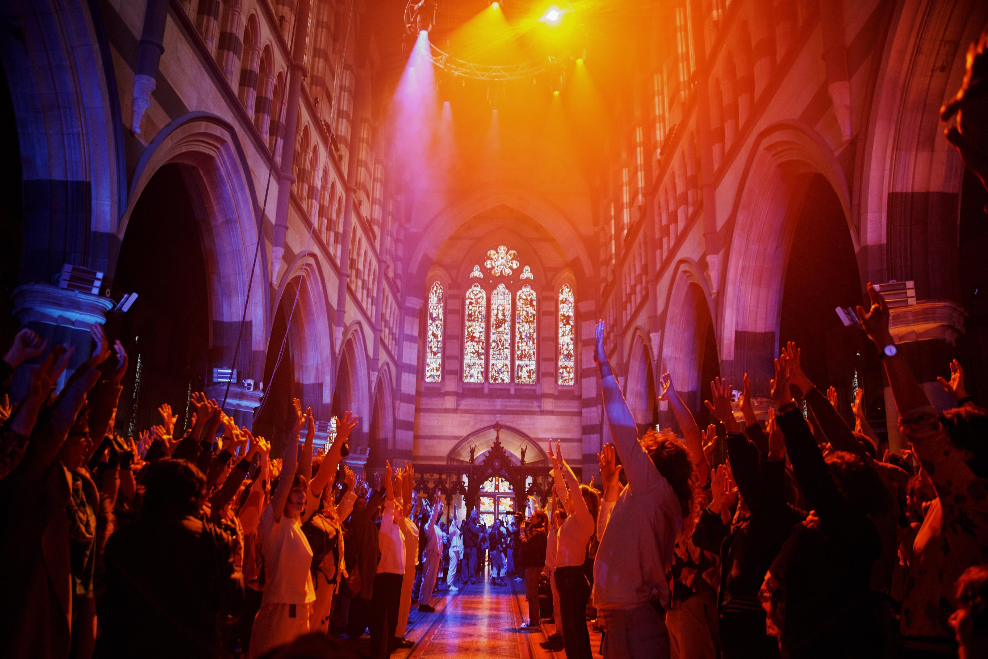 Two groups of people raise their arms in the air in unison.