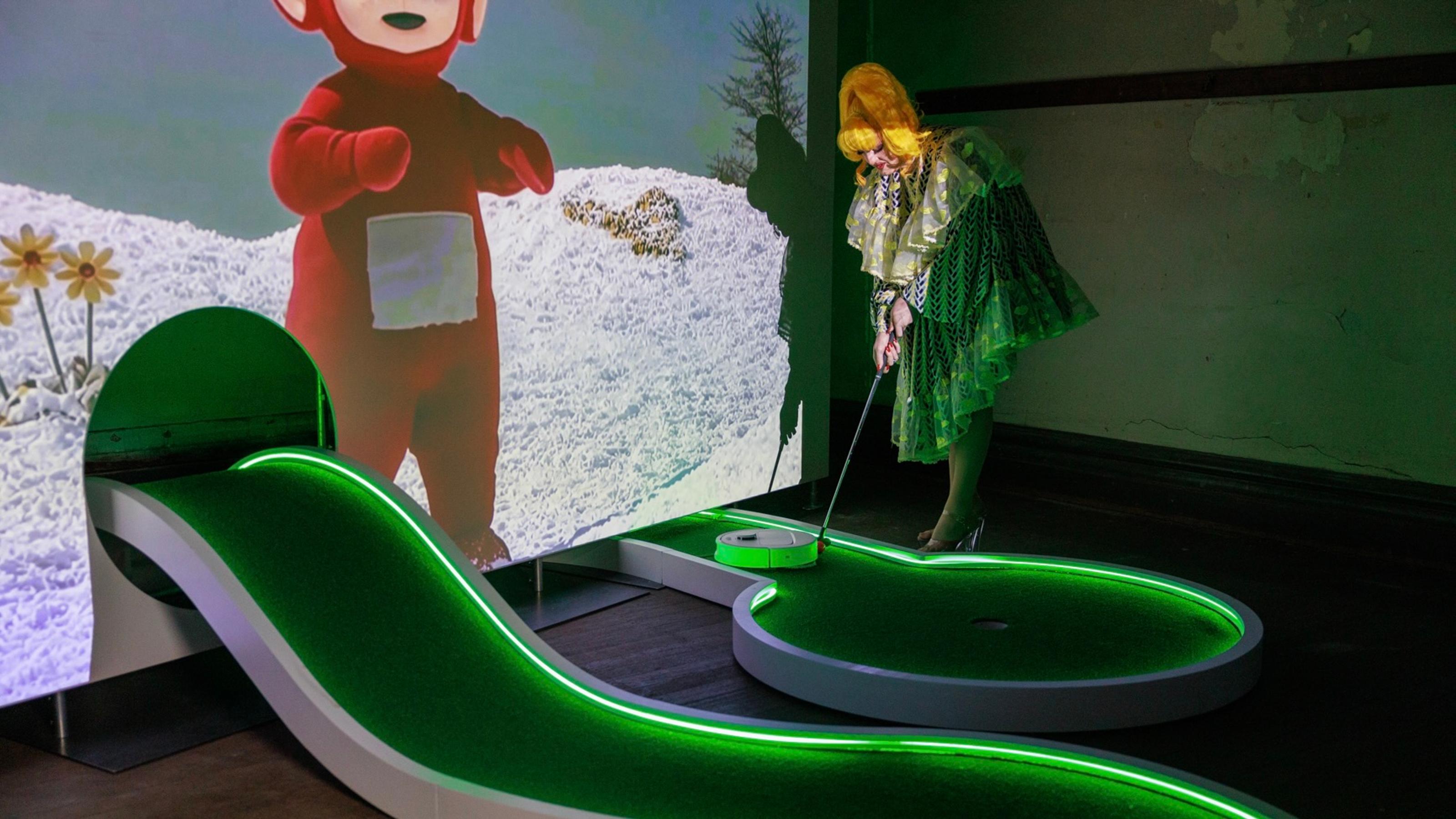 Someone lining up to try Soda Jerk's Swingers hole, a winding carpet with a projected teletubby watching over