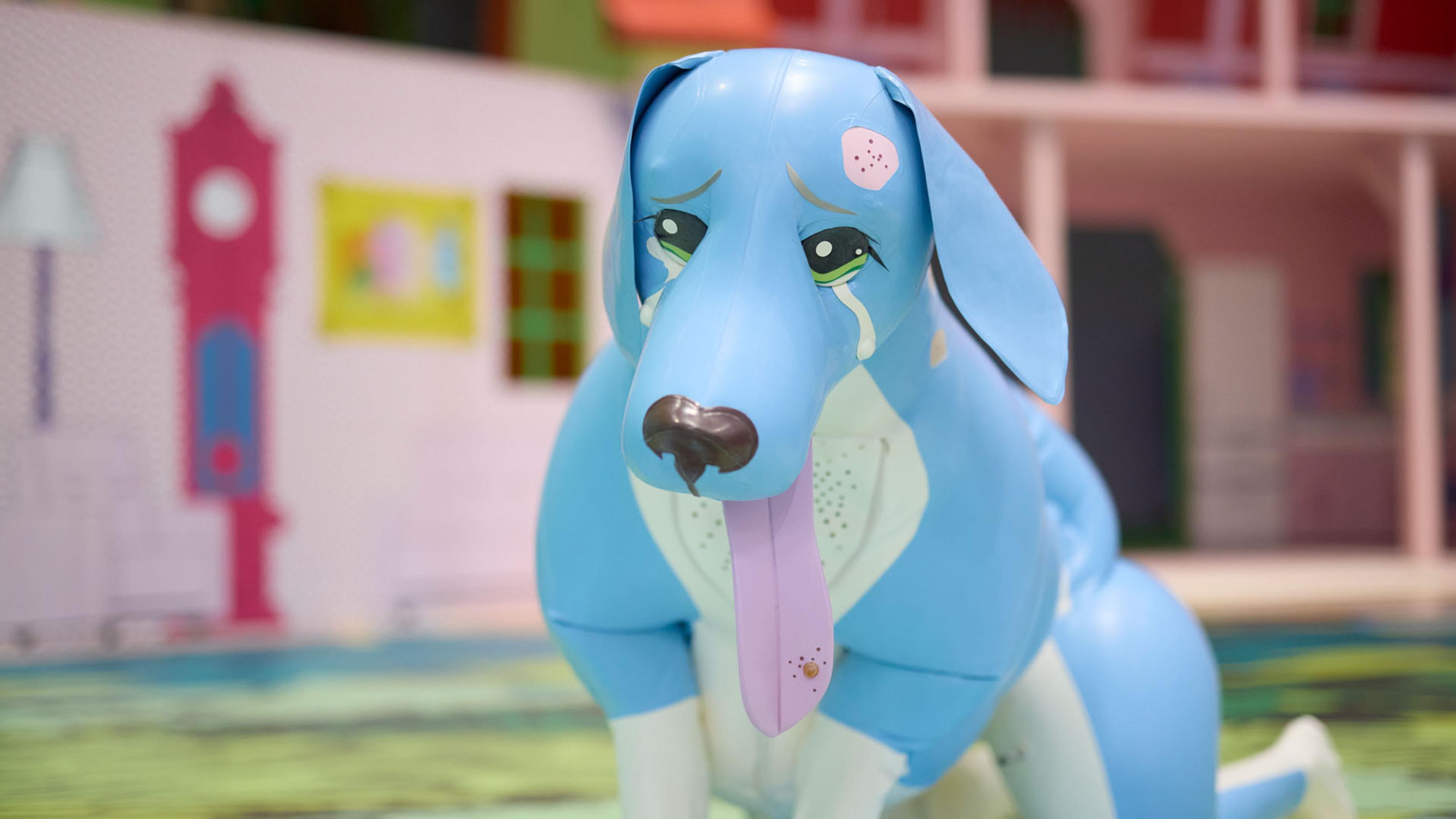 A performer wearing a cartoonish, inflatable dog costume crawls on all fours