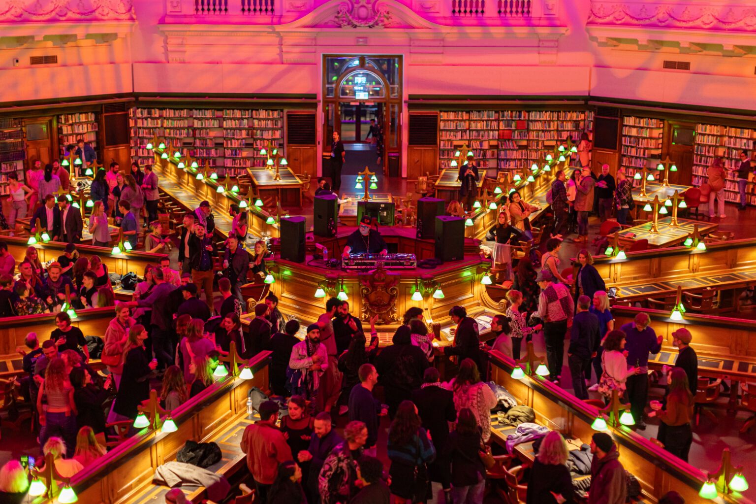 A vibrant library buzzing with energy, people engage in chatting and connecting. The music filling the space with an exciting, festival atmosphere.