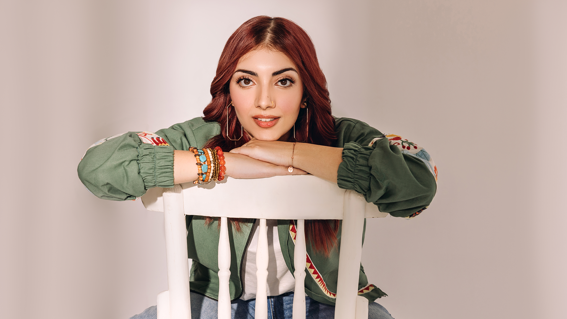 Annural Khalid sits on a chair, with her arms resting against the back frame.