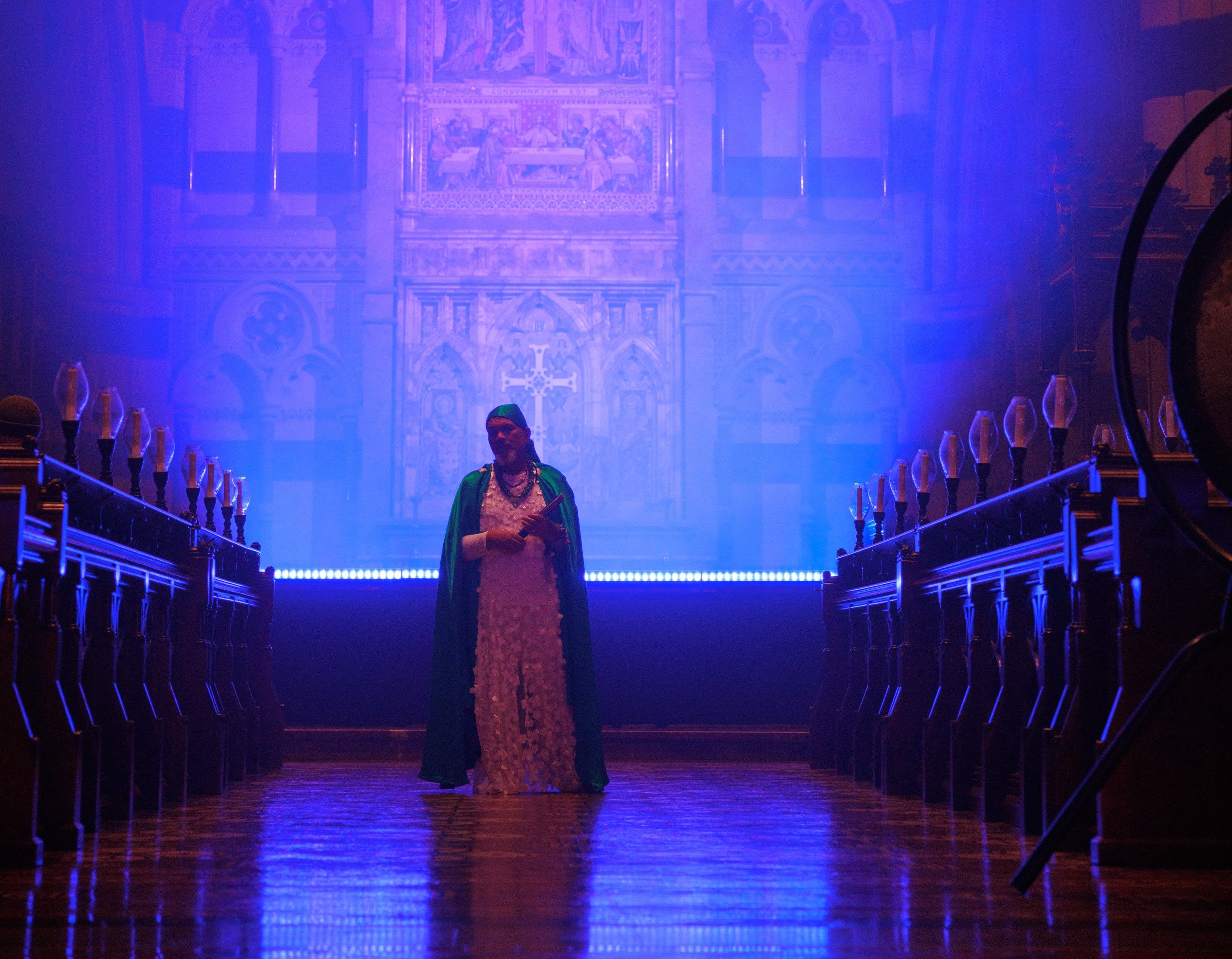 A figure standing holding a flute, backlit. 