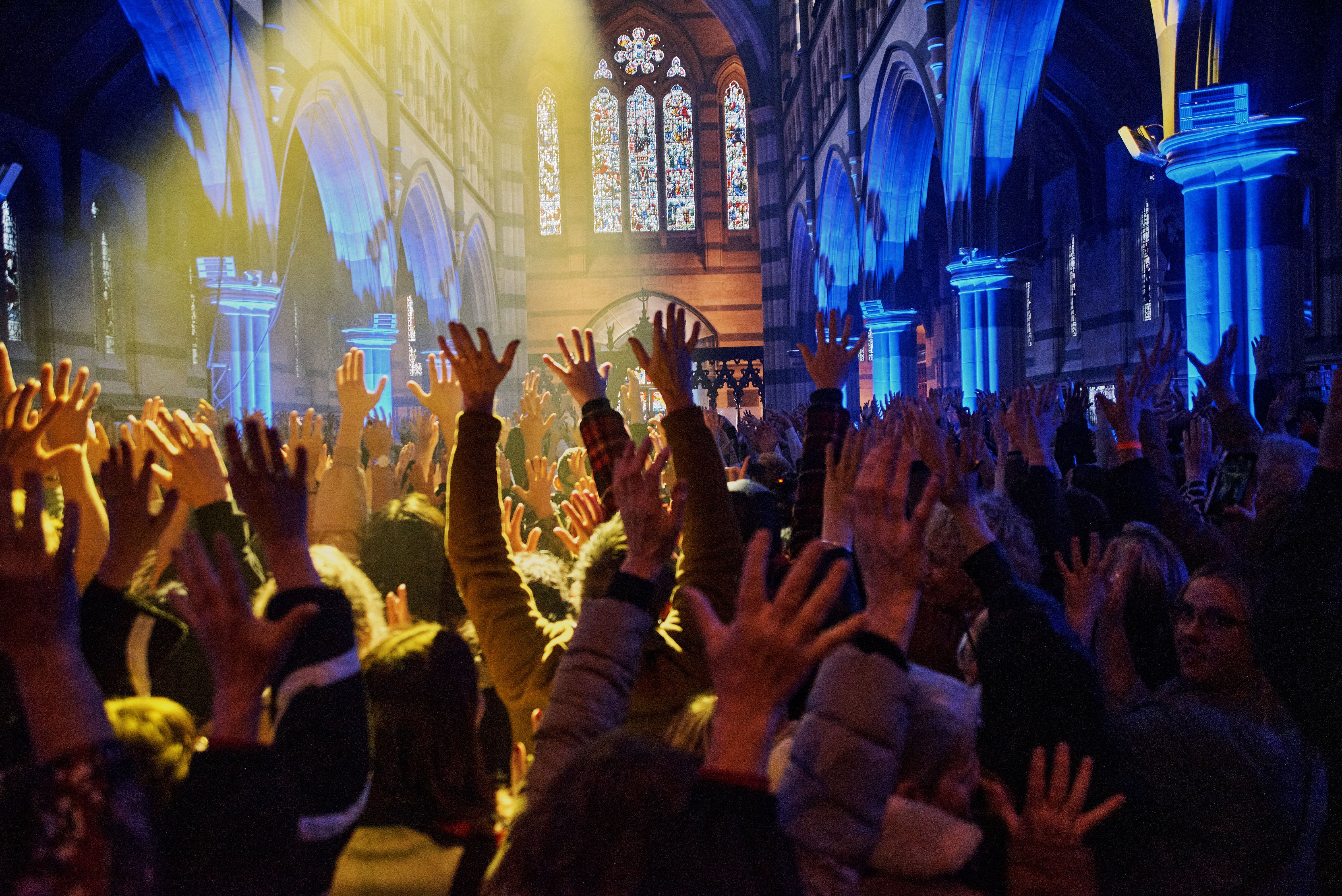  A crowd of people raise their arms in the air