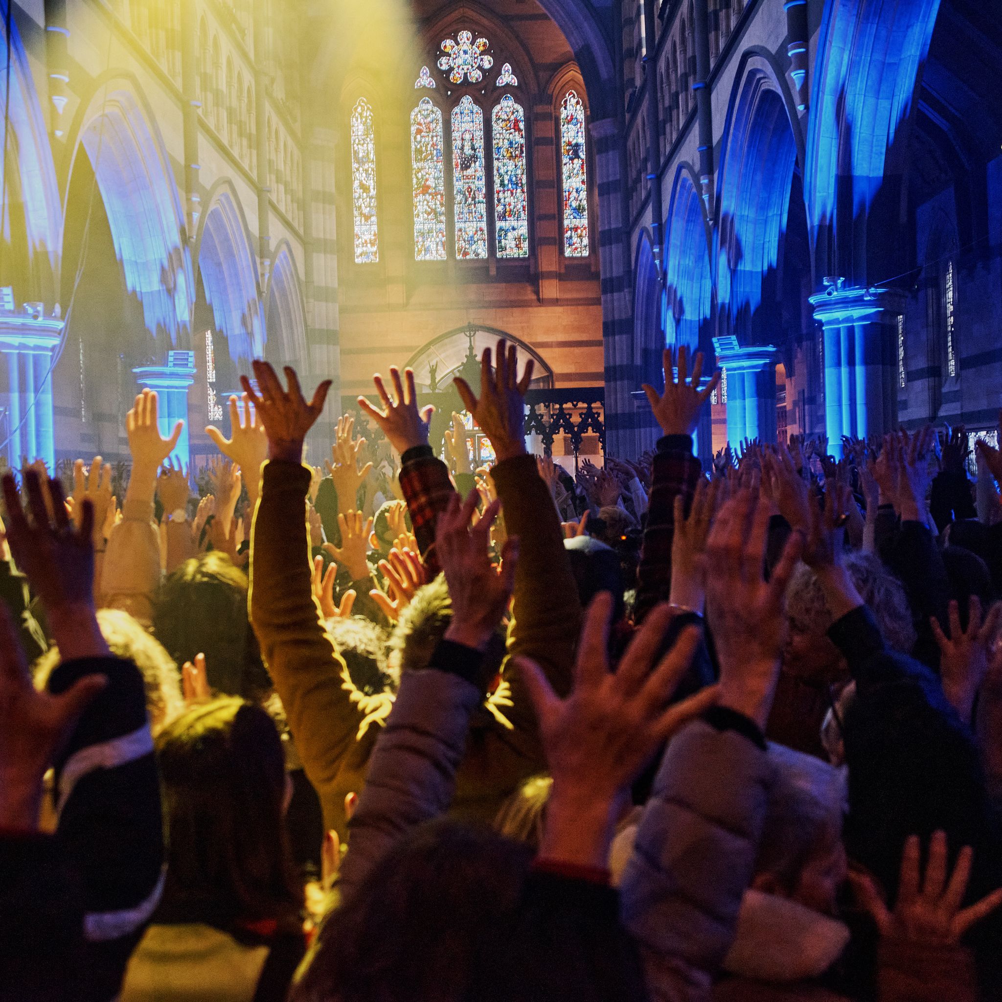 A crowd of people raise their arms in the air