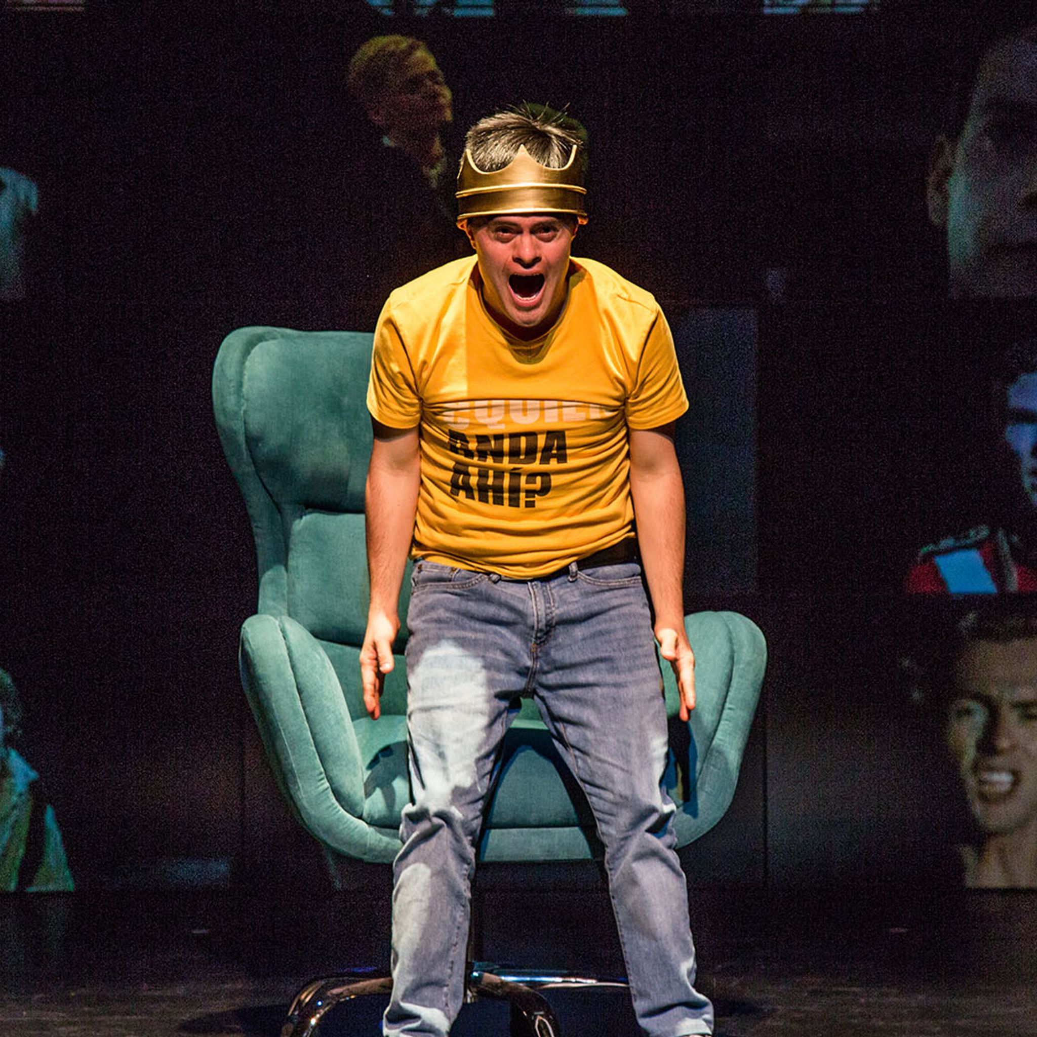 An actor wearing a crown stands on stage screaming.