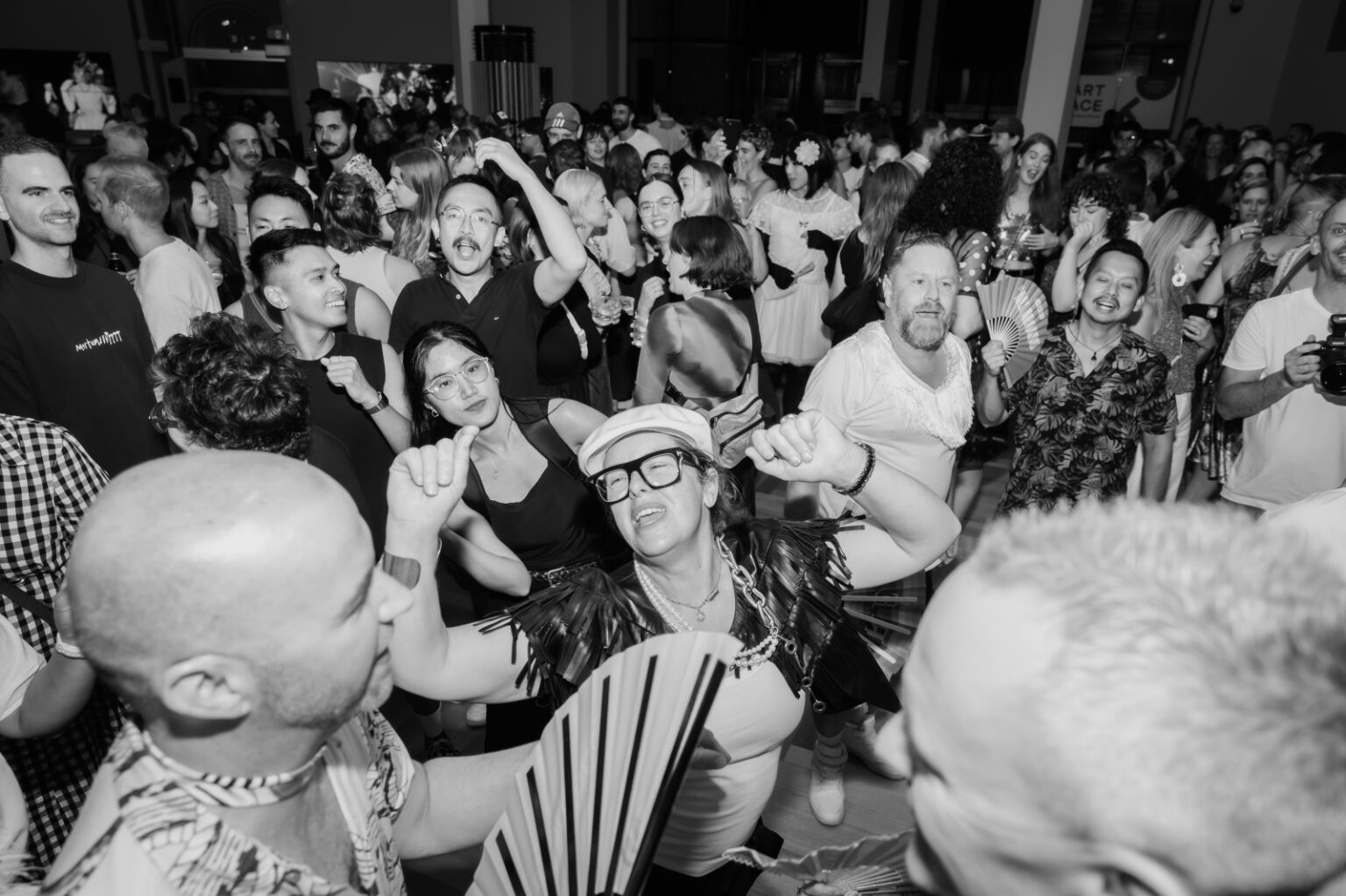 People squeeze together, having fun and dancing, and feeling the music as it pulses through the space.