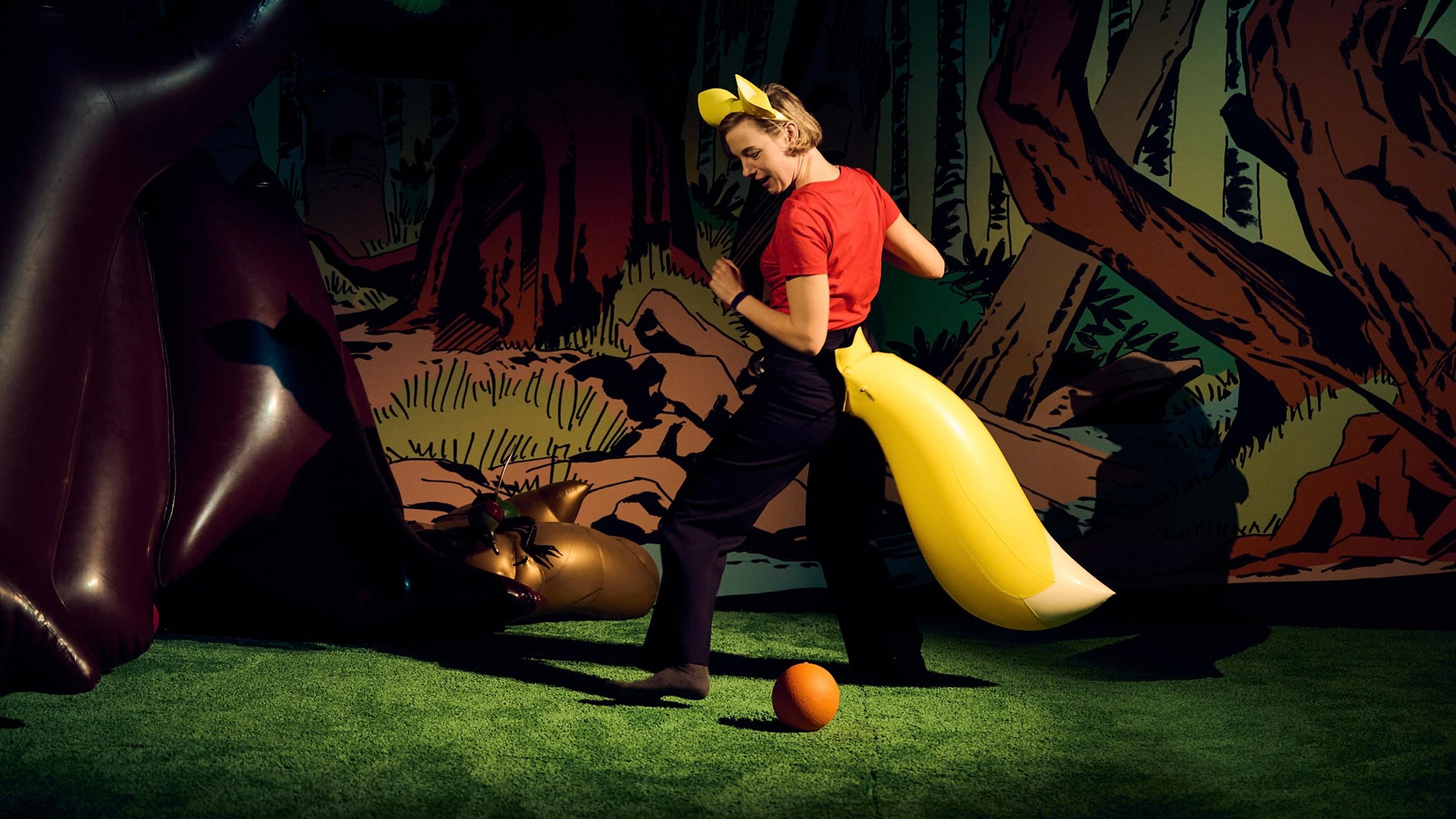 Someone in an inflatable tail attempting to hit a ball in an inflatable forest