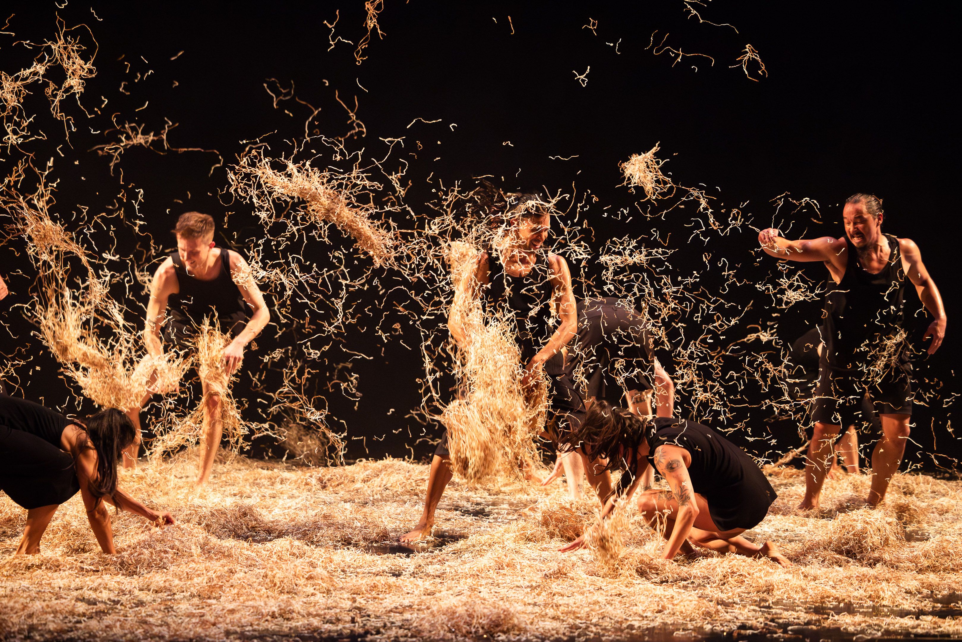 Six actors, standing in hay, throw it around the stage and at each other