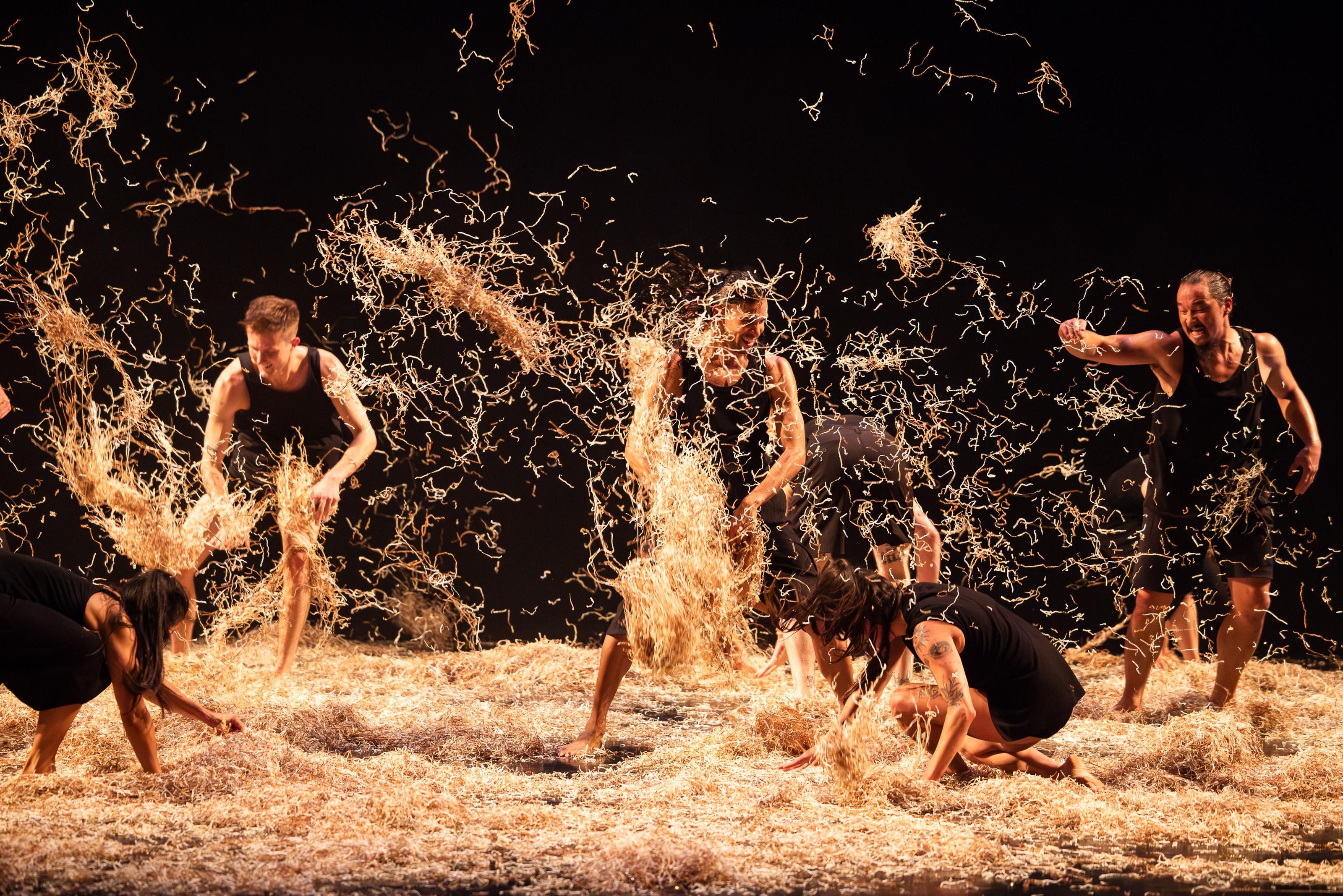 Six actors, standing in hay, throw it around the stage and at each other