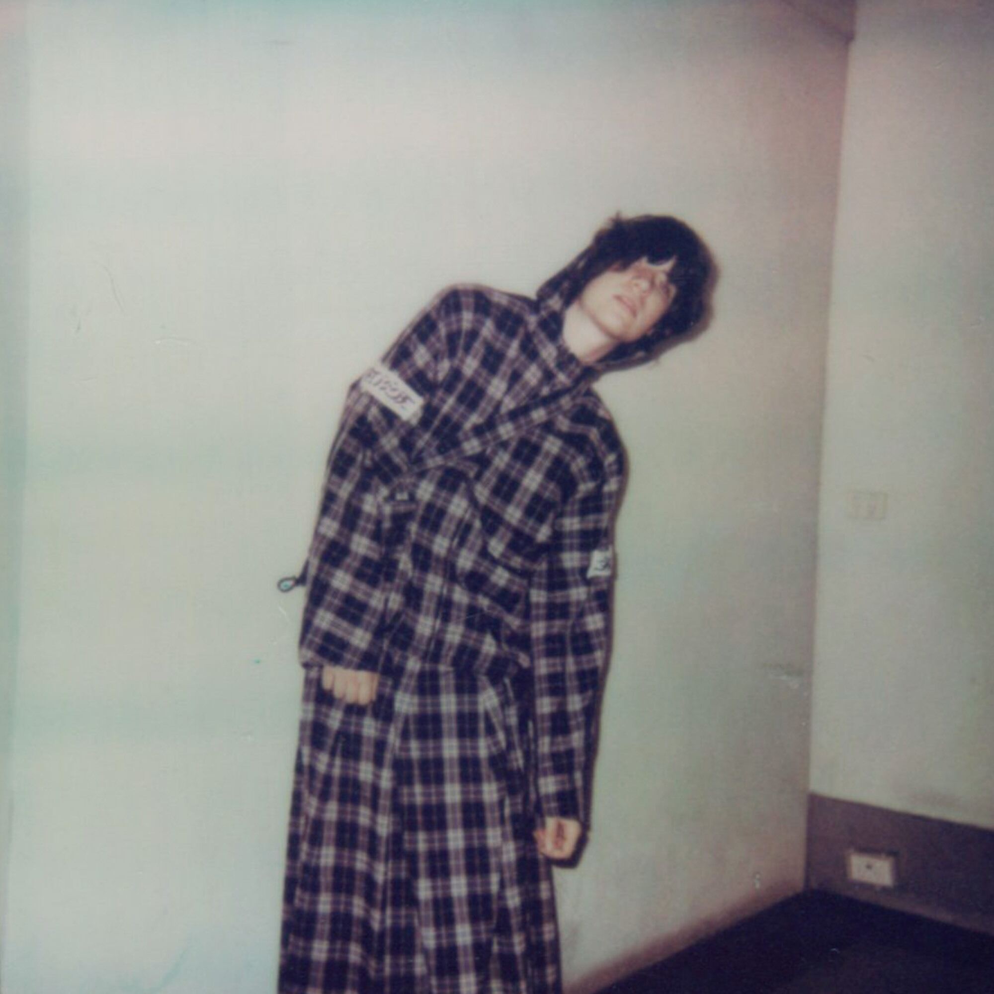 Sidney Phillips is standing and leaning to the right, wearing a checkered (caro) outfit.