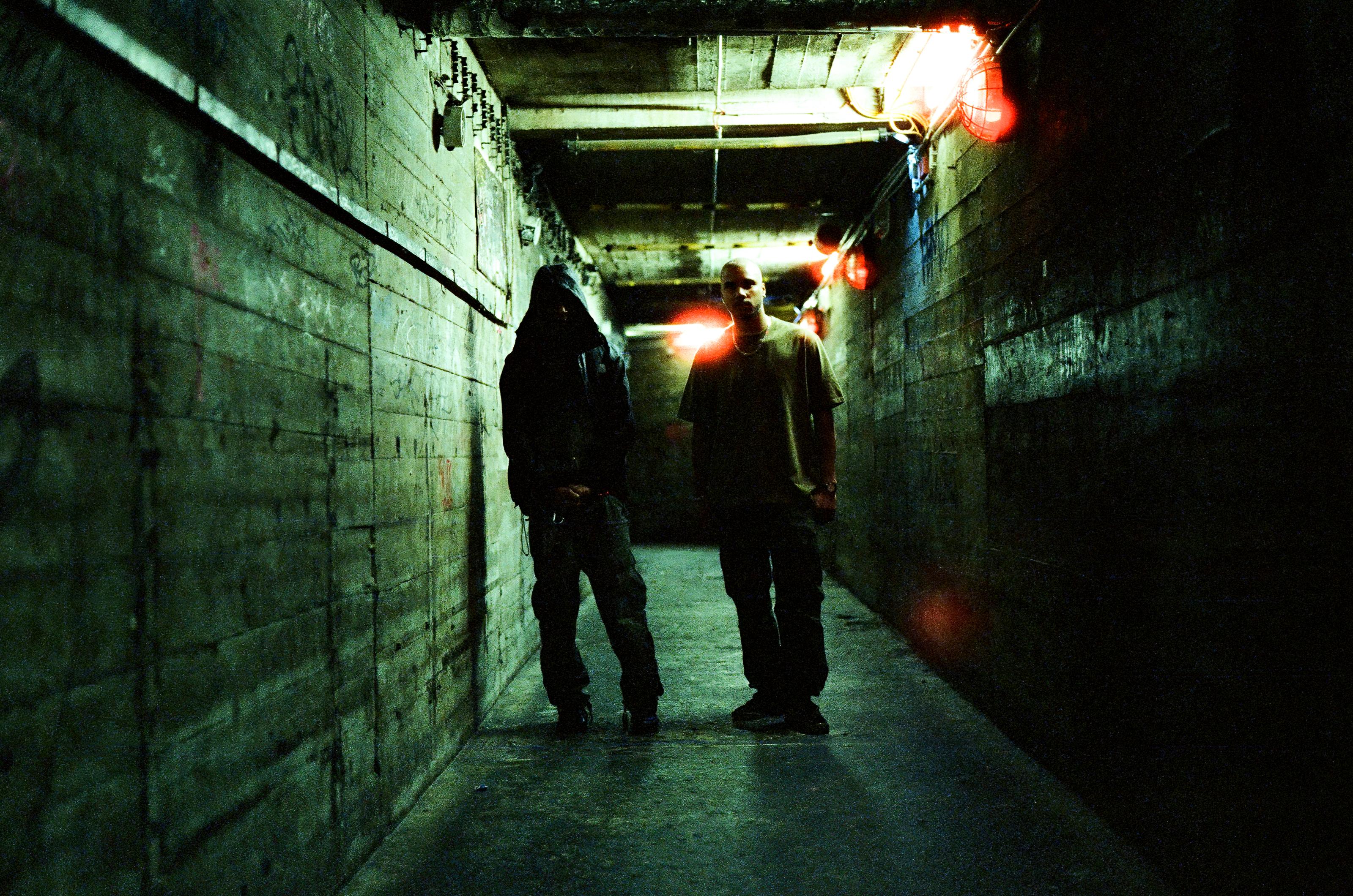 Tikiman & Richard Akingbehin stand in a dimly lit tunnel.