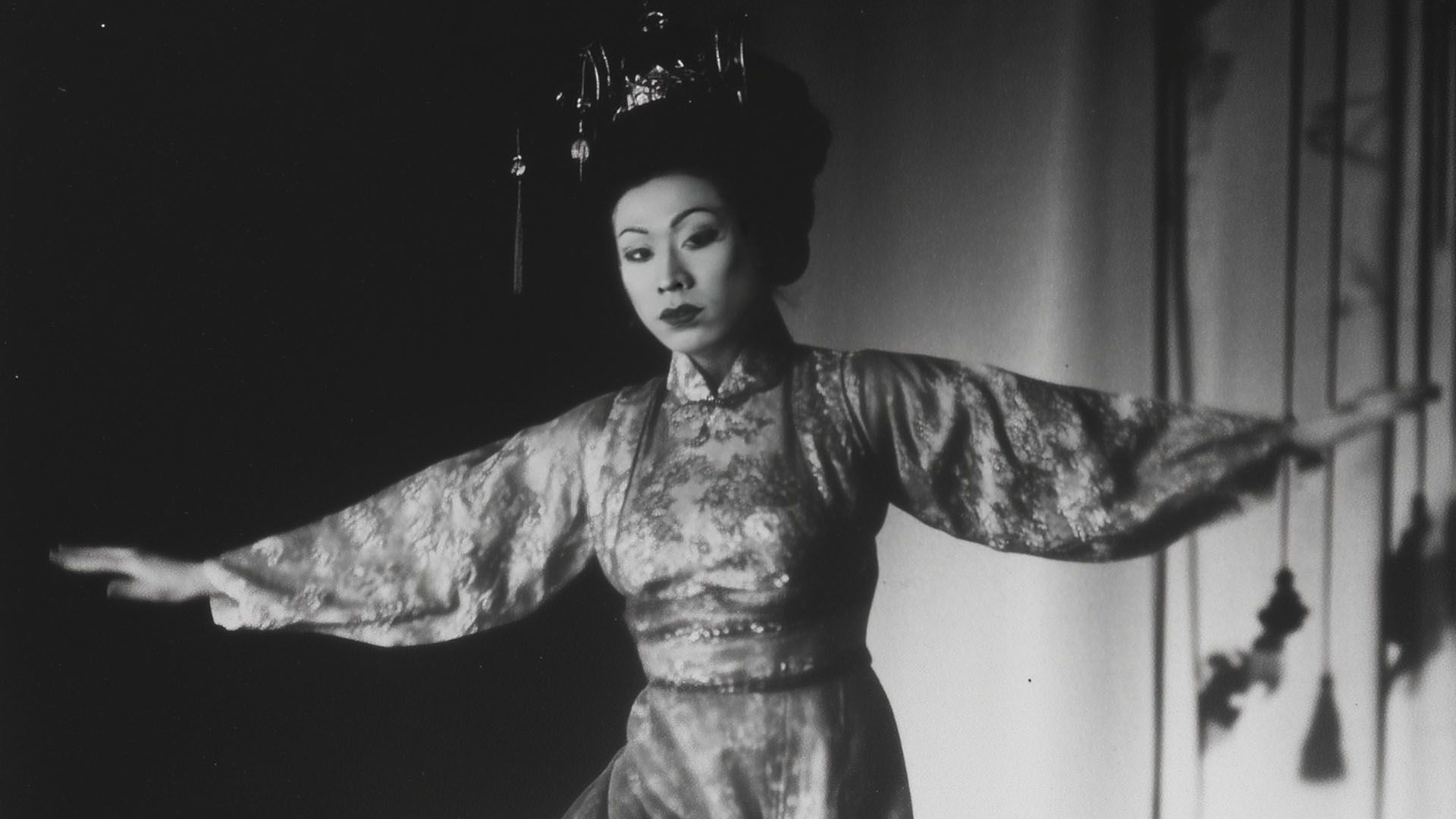 Gazing towards the camera, a woman spreads her arms like wings.