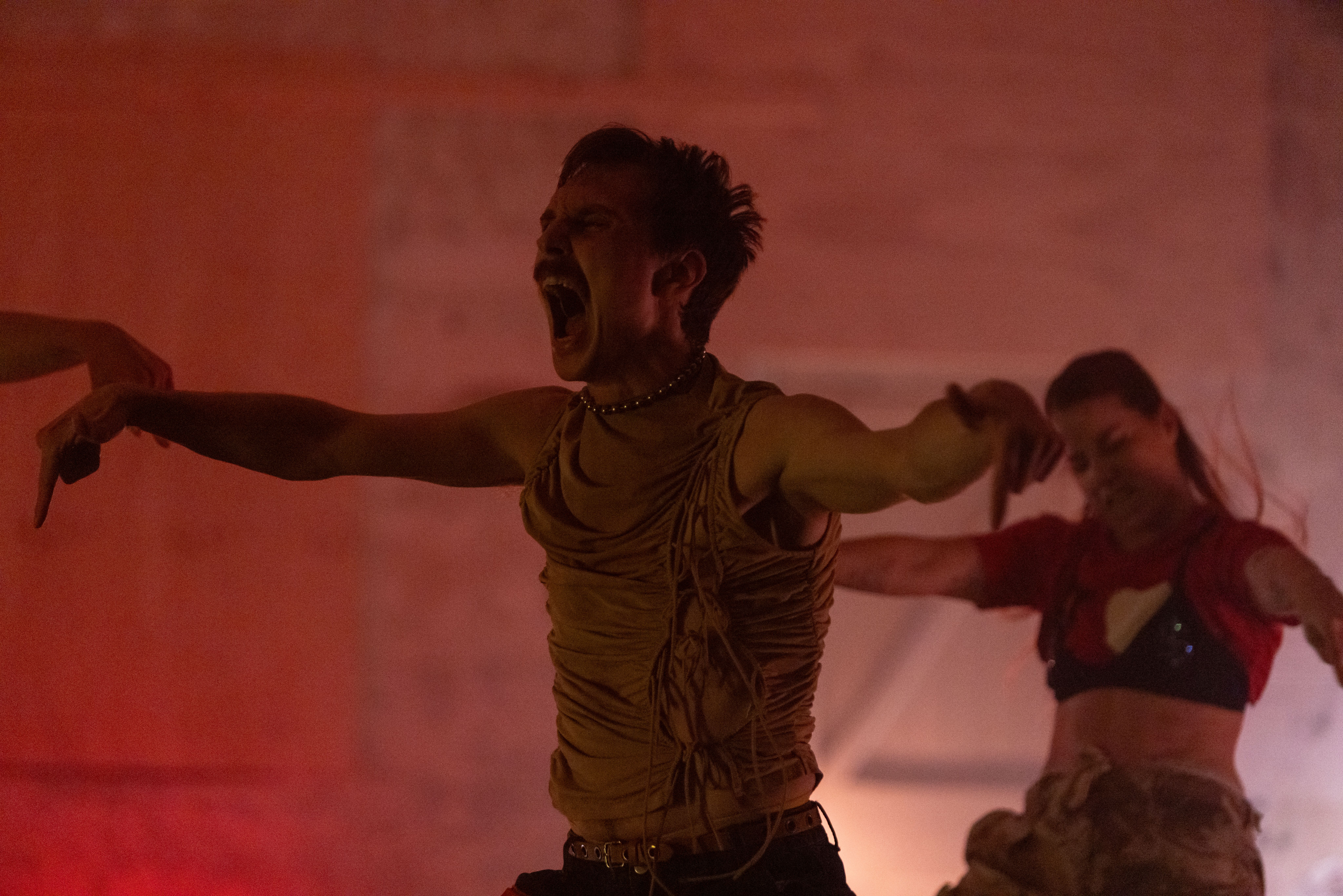 Two dancers pose with their arms extended out, their fingers pointing down, and appear to be screaming.  