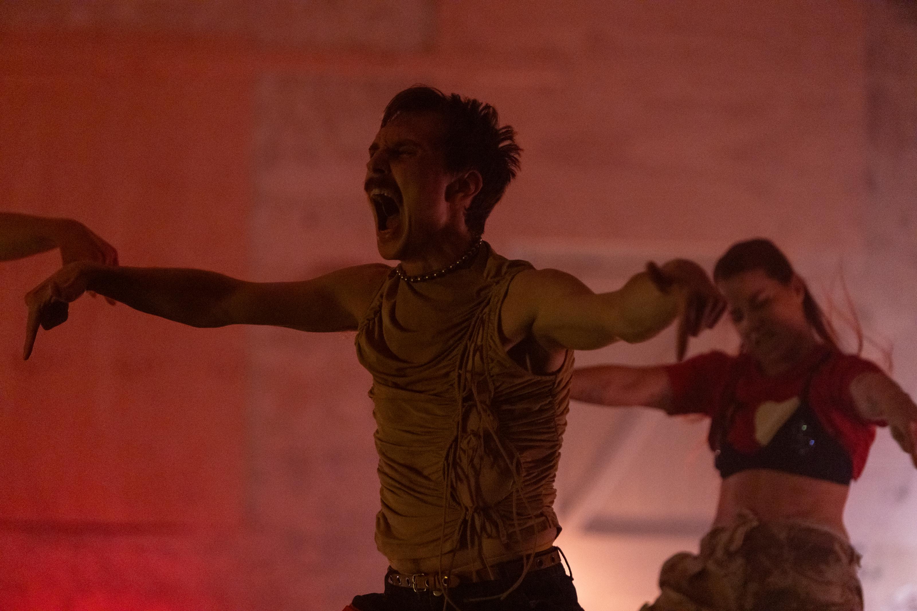 Two dancers pose with their arms extended out, their fingers pointing down, and appear to be screaming.