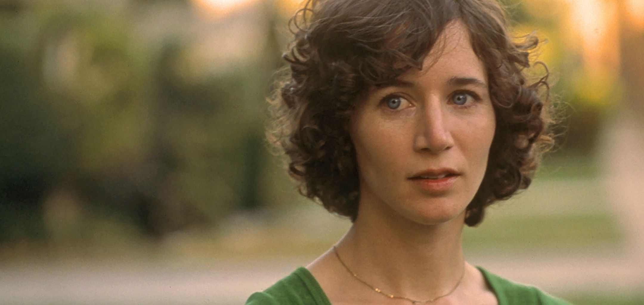 A still from Me and You Everyone We Know (2005). A person with short, curly brown hair and a neutral, slightly concerned expression looks ahead.