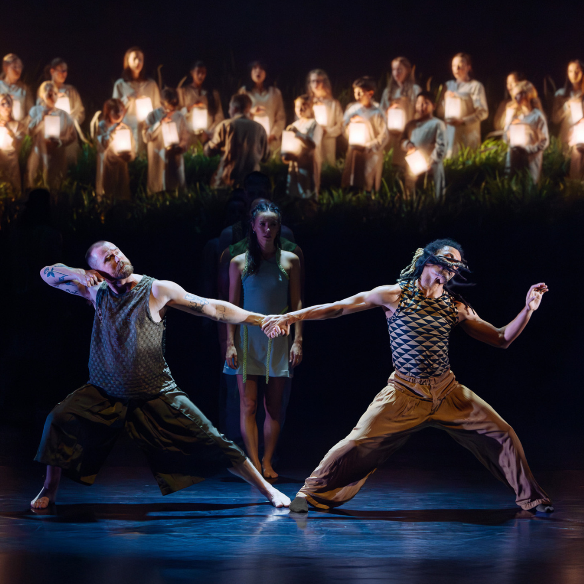 Two dancers stretch outwards whilst keeping their inner hands and feet connected.