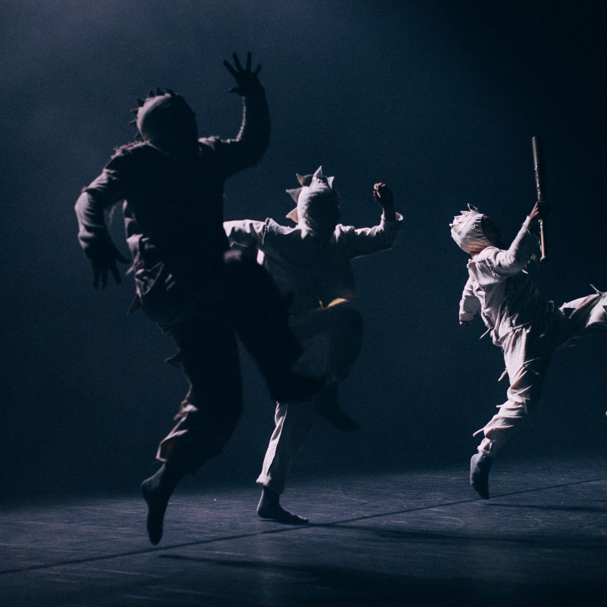 A silhouetted group of dancers leaping in angular shapes
