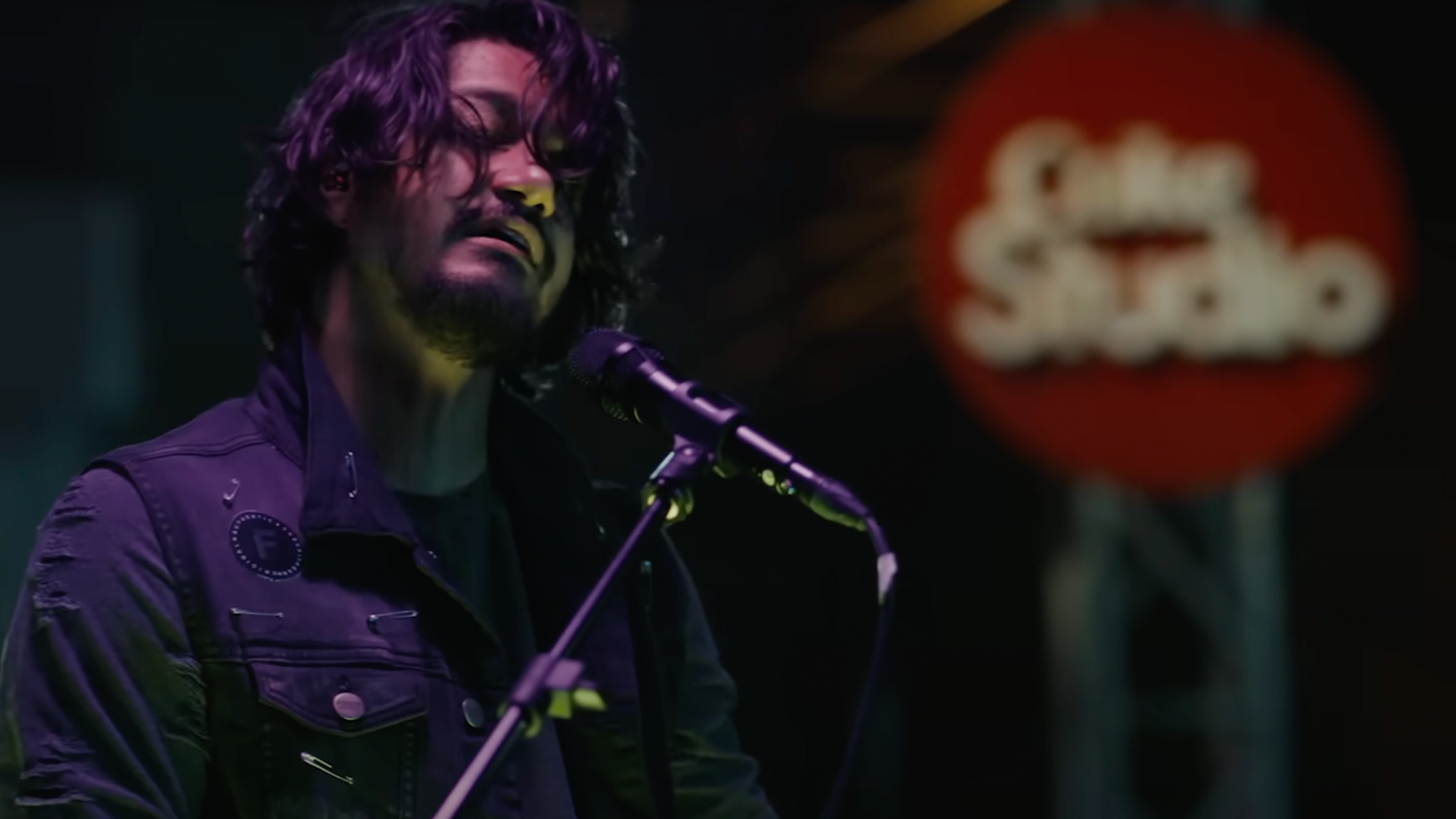 Sherry Khatak sings with eyes closed, while performing into microphone.