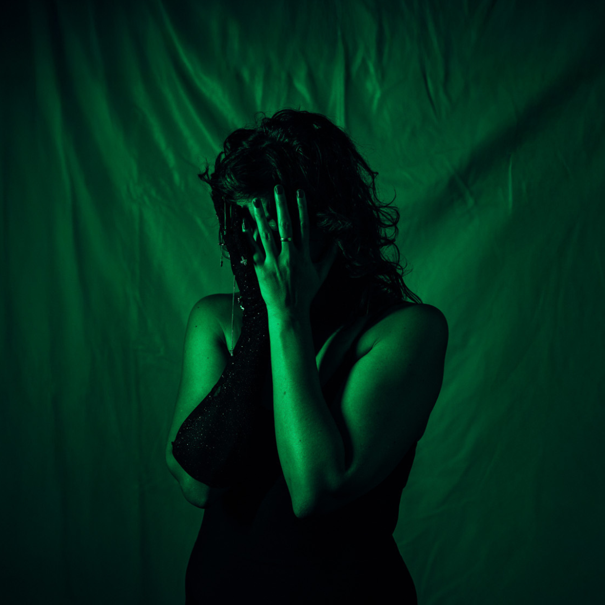 Close-up of a dancer with wavy hair covering their face, obscuring their features, against a fabric backdrop.