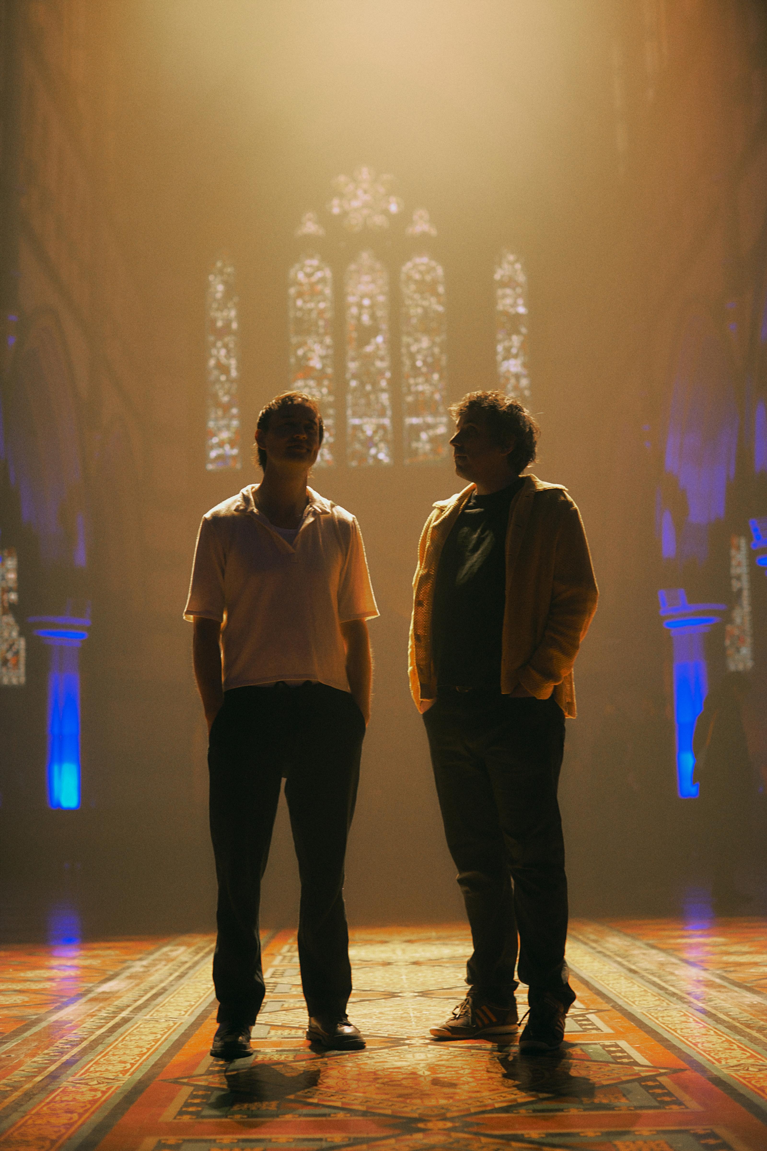 SHOUSE’s Ed and Jack stand side by side backlit and silhouetted.