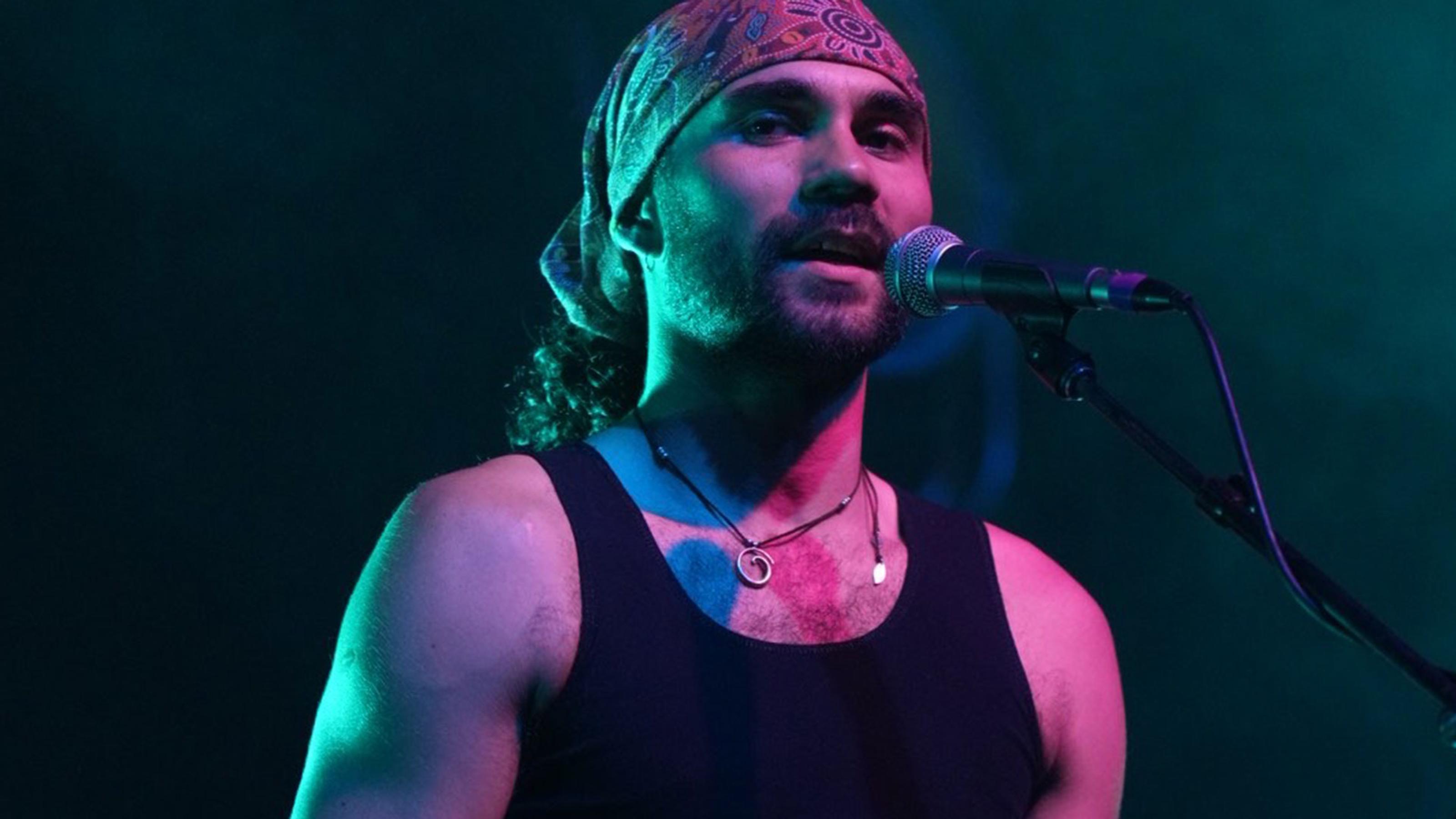 Brother Nelson sings into a microphone, looking into the camera