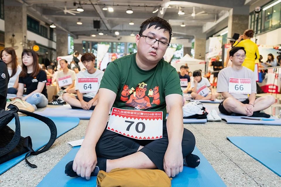 Competitor sits down with their legs crossed, staring into space with blankless emotion 