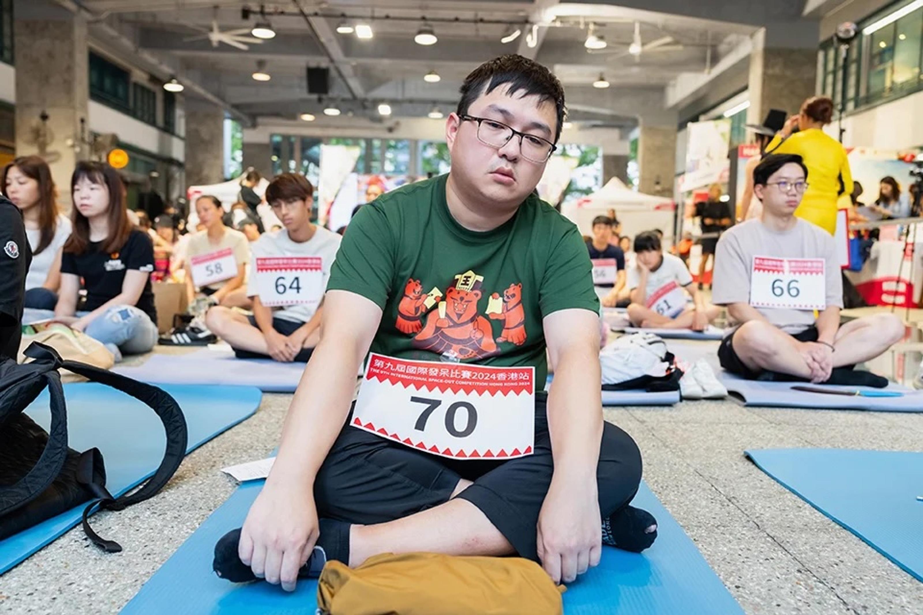 Competitor sits down with their legs crossed, staring into space with blankless emotion